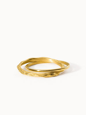 Zwei goldene Ringe mit wellenförmigem Design von PURELEI, elegant und modern.