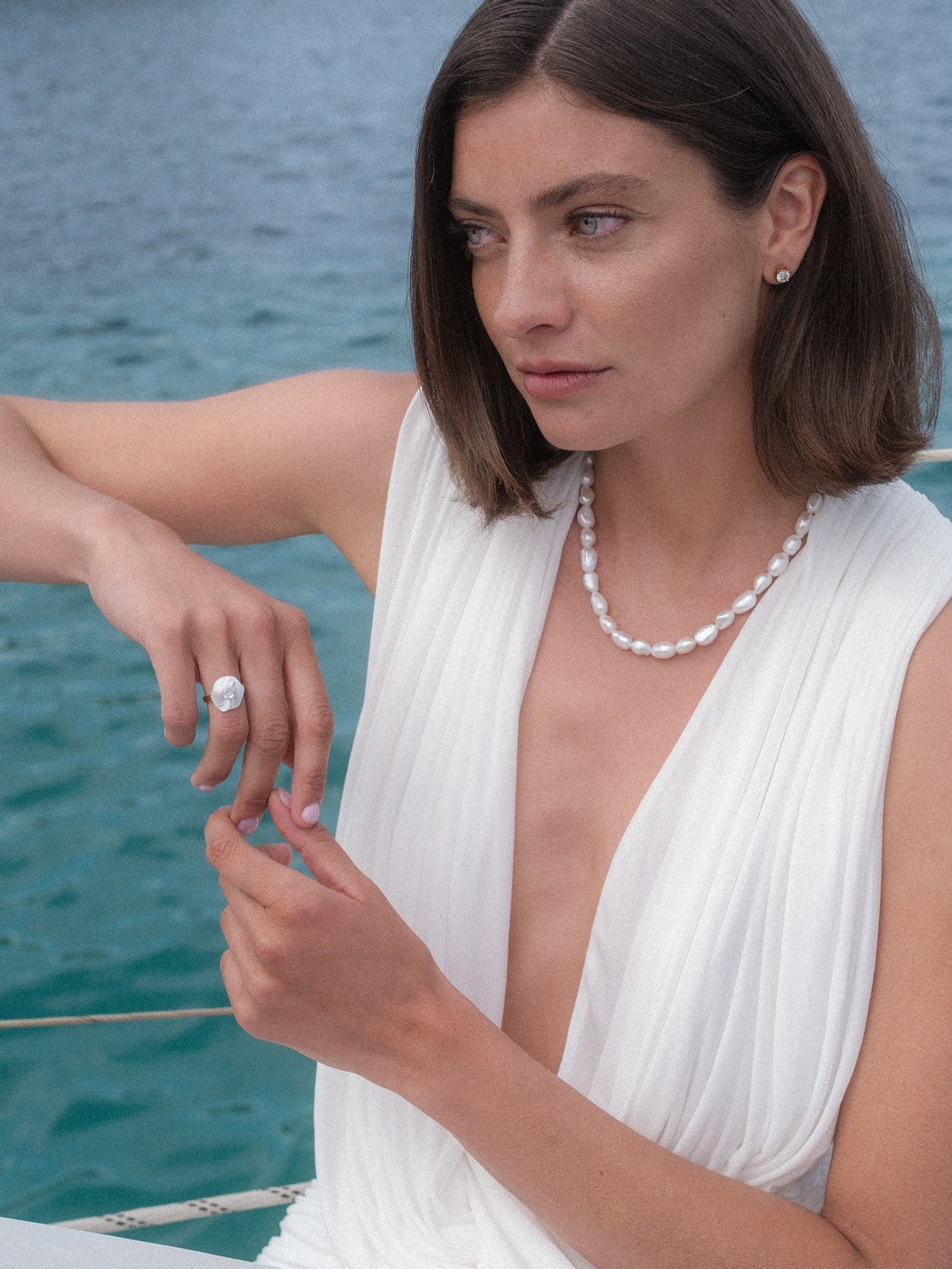 Allure Ring mit Stein, vergoldet, Muschel-Blütenmotiv mit weißem Zirkonia, getragen am Meer, PURELEI Stil