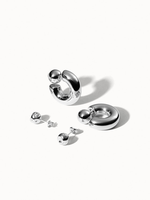 Silberne Creolen und Ohrstecker von PURELEI, glänzend und modern, elegant inszeniert.