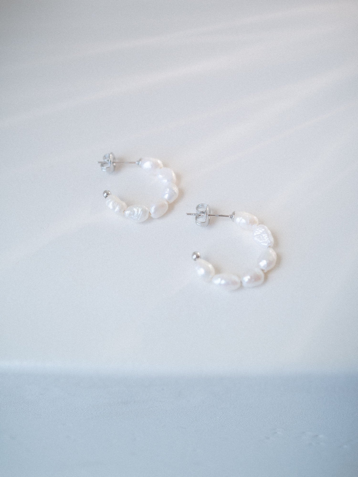 Organic Pearl Perlenohrringe mit natürlich geformten Süßwasserperlen auf schlichtem weißem Hintergrund, PURELEI.