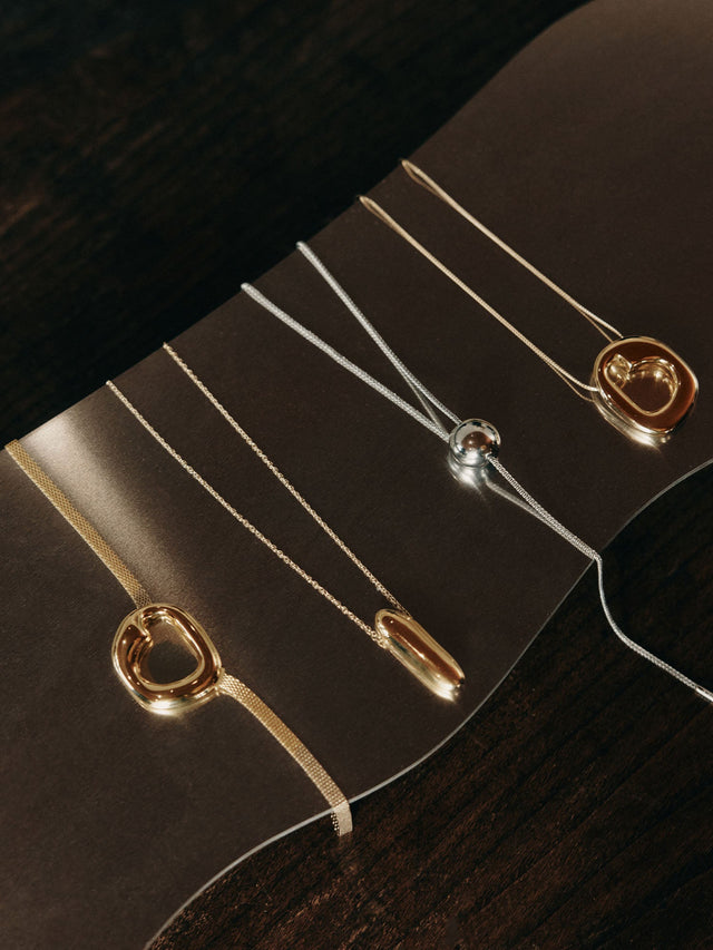 Silberne Ketten mit modernen Anhängern auf dunklem Hintergrund von PURELEI.