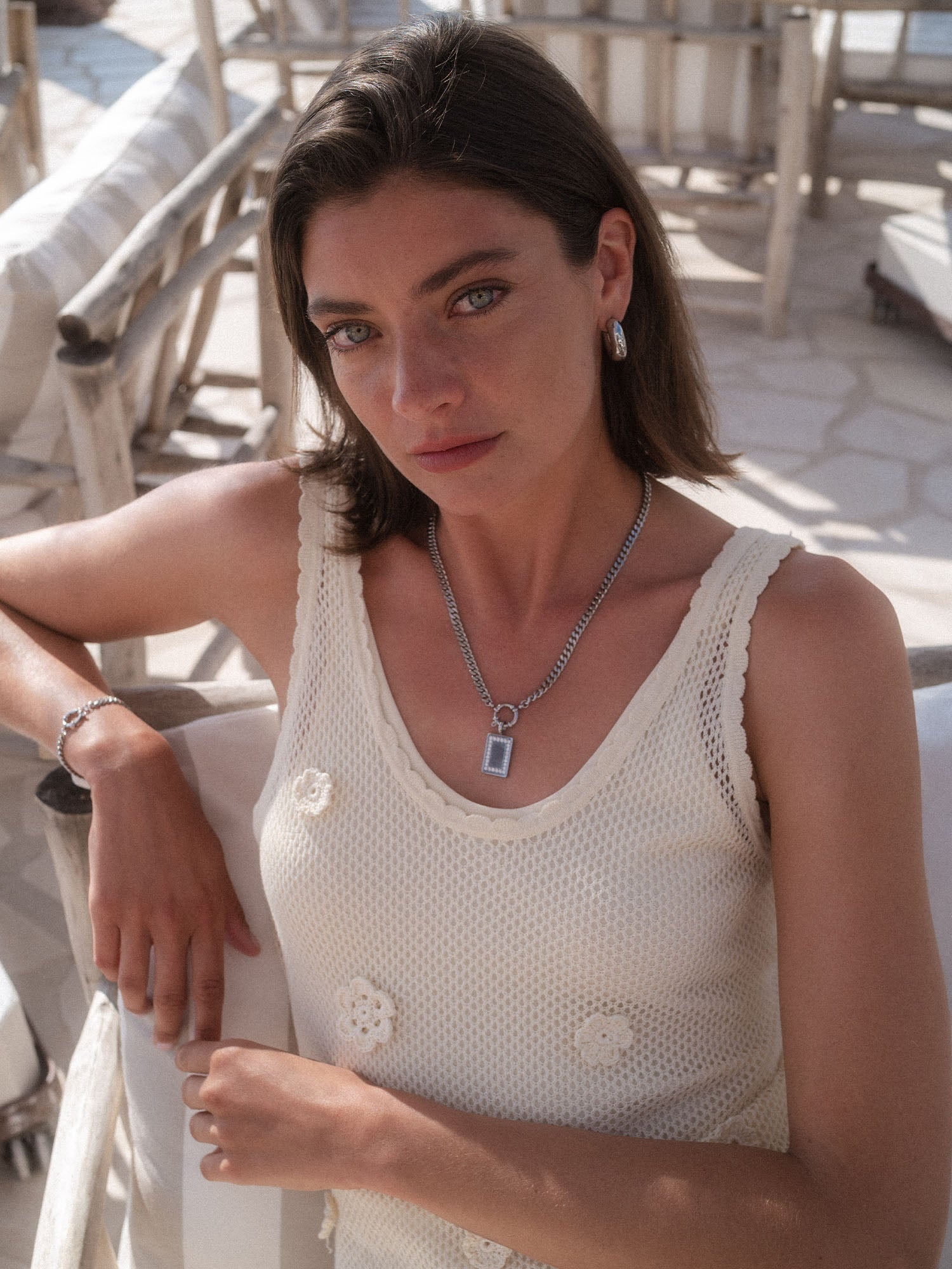 PURELEI Glimmer Charm in Silber mit Zirkonia, rechteckig, getragen in sonniger, eleganter Strand-Atmosphäre.