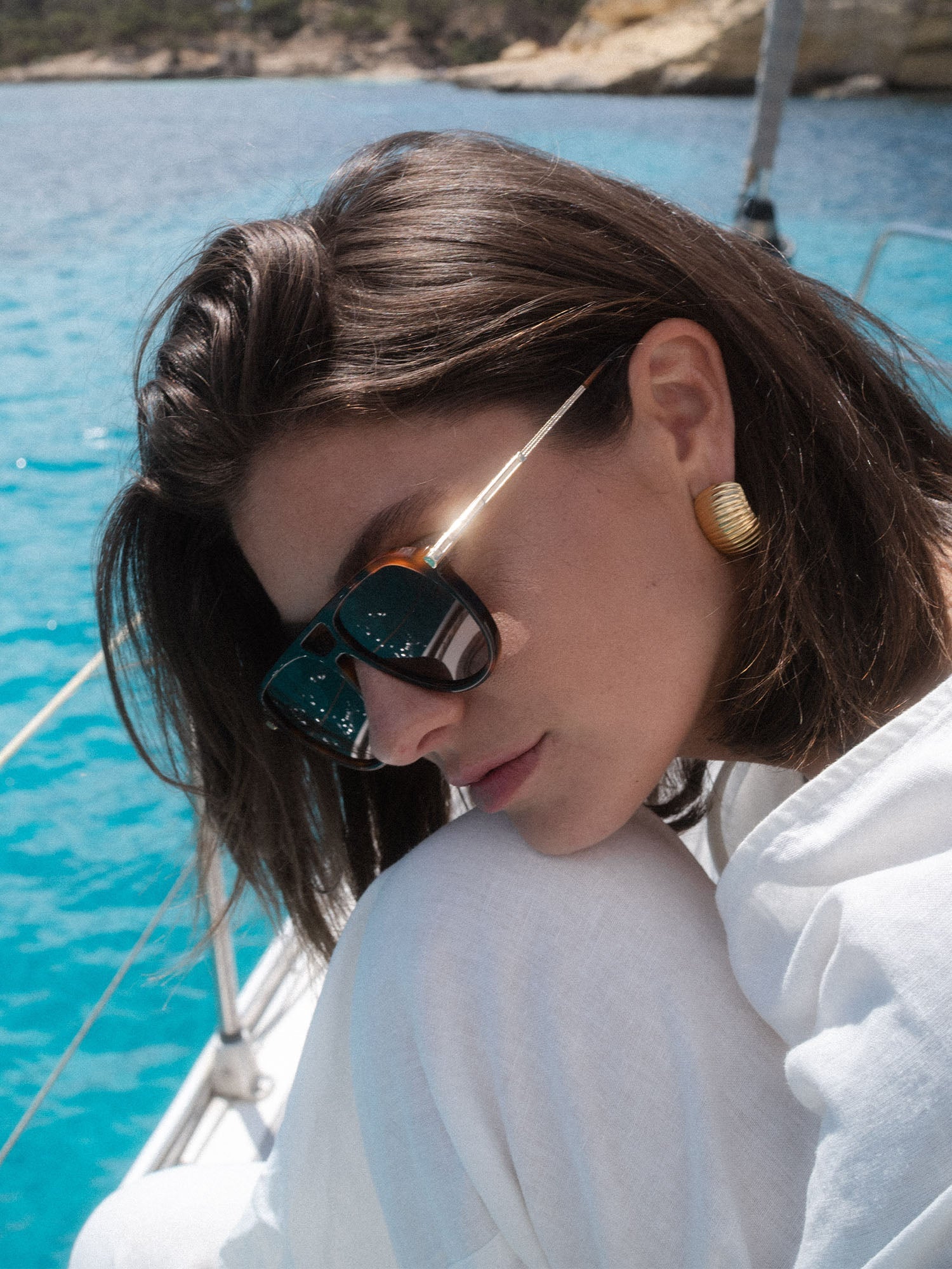 PURELEI Palm Beach Sonnenbrille im braunen Schildpatt-Look mit goldenem Bügel, elegant am Sommerstrand getragen.